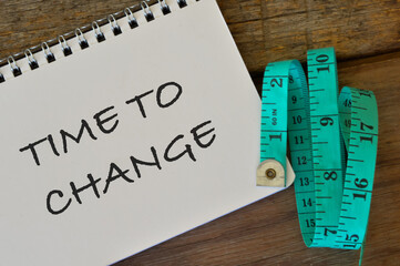 Top view of measuring tape and notebook written with TIME TO CHANGE.