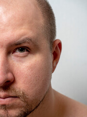 portrait of half the face of a middle-aged man looking at the camera. Beard, little hair on the head. Vertical photo