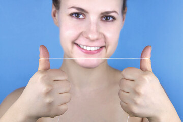 Smiling woman holding dental floss in front of her.