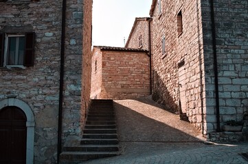 Light filters through the brick houses of a small medieval Italian village (Pesaro, Italy, Europe)