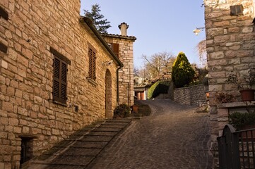 A staircase in a medieval Italian village with brick houses and floral decorations (Pesaro, Italy, Europe)