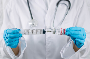 Doctor with a stethoscope holding vaccine syringe of coronavirus