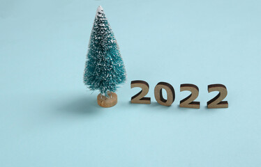 2022 and mini christmas tree on blue background. Christmas, new year composition