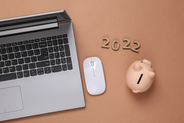 2022 andlaptop, Piggy bank on brown background. Economy, new year composition. Budget of the year