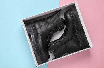 New Fashionable stylish leather female boots in box on pink blue background. Top view