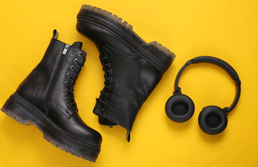 Black Leather boots and headphones on yellow background. Top view. Flat lay