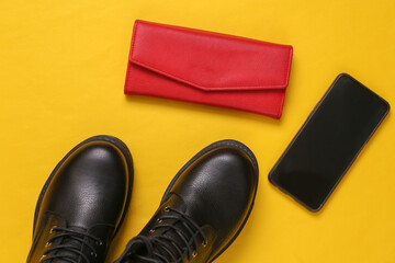 Black Leather boots, smartphone and wallet on yellow background. Top view. Flat lay