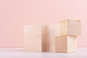 Set of wooden cube podiums on white wood table and pastel pink wall for presentation and product display.