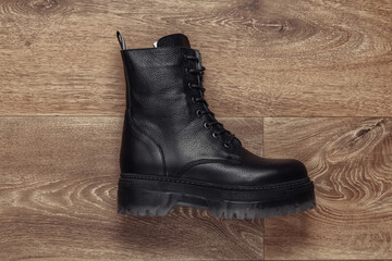 Fashionable stylish leather female boot on wooden floor. Top view