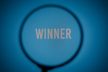 Inscription winner on blue screen of the monitor through magnifying glass