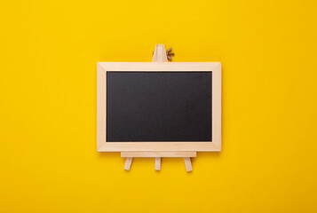 Mini blackboard on yellow background. Empty, blank chalkboard with copy space. Business, education, learning concept.