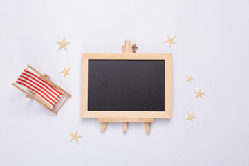 Beach vacation. Mini deck chair, starfishes and empty chalk board on white background. Copy space