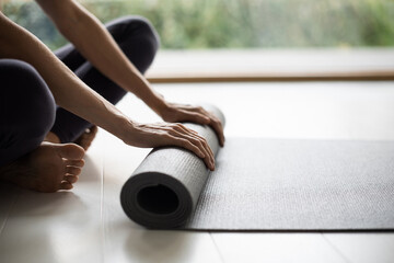 Woman rolling up exercise mat after doing yoga or fitness closeup panoramic . Training, fitness,...