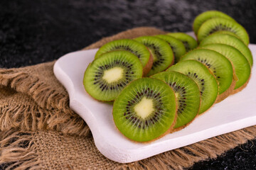 Kiwi slices on a white wooden board.
Close-up.