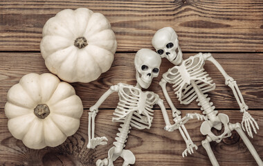 White mini pumpkins and skeleton on a wooden table. Halloween theme