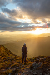 silhouette of the man at the top of the mountains peak looking at sunset