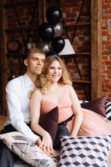 A young man and a woman embrace in a loft-style interior