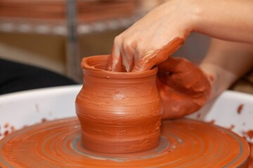 Fototapeta na wymiar Clay jug on a potter's wheel. The hands of a master potter shape the clay from the inside