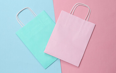 Paper shopping bags on blue pink pastel background. Top view