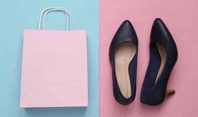 Shopping bag with high heel shoes on blue pink pastel background. Shopping concept