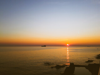 Genova, Italy - February 26, 2021: Beautiful sunset over the sea of Genova in winter days. Amazing red and orange coloured sky reflecting into the water.