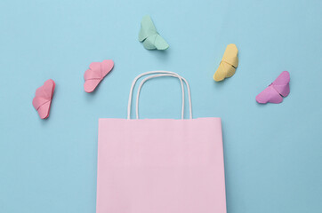 Shopping bag and origami butterflies on a blue background. Spring sale. Top view