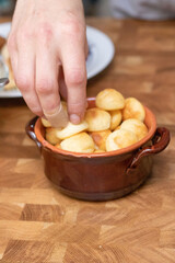 Hands holding pan de queijo, a Brazilian mini cheese bread finger food, party food and snack