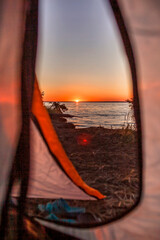 Family summer getaway. Beautiful sunrise on the wild sea beach at campsite at summer. Healthy lifestyle, green local tourism and safe vacations, mental recreation, outdoors, view from camping tent