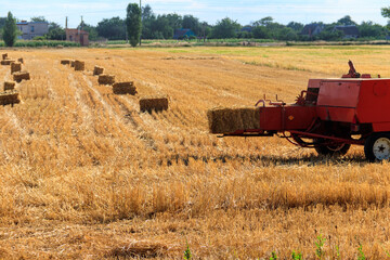 Rectangular baler discharges a straw bale in a field during the harvesting process