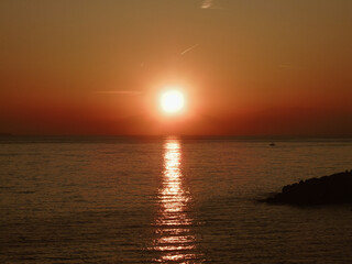 Genova, Italy - February 26, 2021: Beautiful sunset over the sea of Genova in winter days. Amazing red and orange coloured sky reflecting into the water.