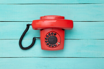 Retro red old fashioned rotary phone on blue wooden table. Top view