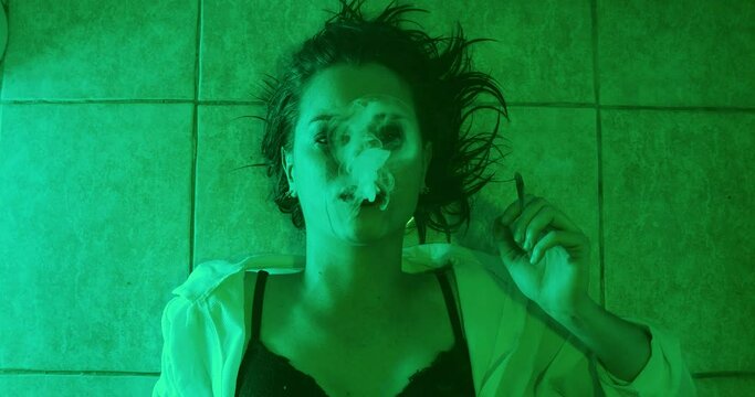 escape from reality - staring girl lying on the ground smokes a joint