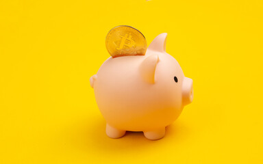 Piggy bank with bitcoin on yellow background
