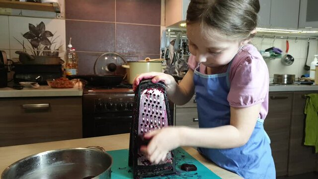 a little girl helps to cook, a girl rubs boiled beets on a grater for making salad and cabbage soup, helping her mother with housework