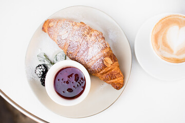 Cup of coffee with croissant and jam