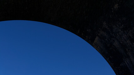 Bright blue sky with dark grey arch above with copyspace