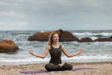 Fototapeta na wymiar Young yogi woman meditates on the beach. Harmony, balance