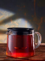 Fruit tea in a glass teapot on a stone background