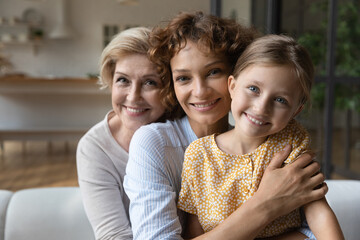 Caring grown woman mother hold on knees hug girl kid while mature female grandmother pensioner...