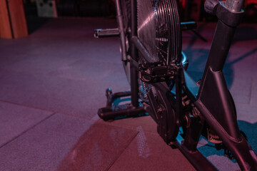 Airbike, professional exercise bike with aerodynamic loading system in red-blue neon light in a modern health class. Cross training