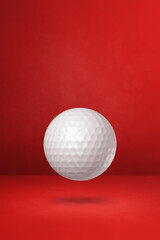 White golf ball on a red studio background