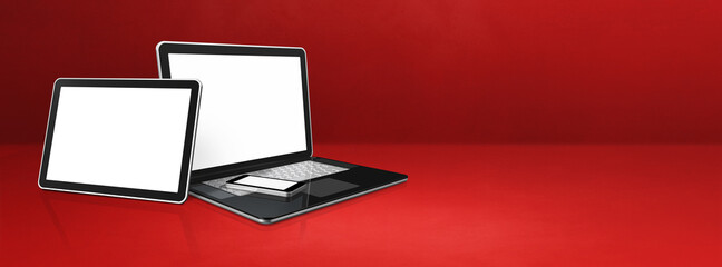 Laptop, mobile phone and digital tablet pc on red office desk. Banner background