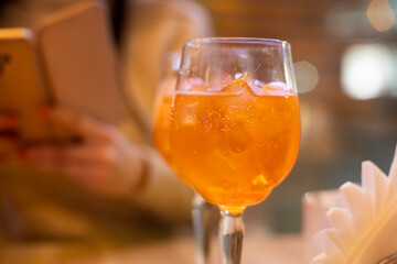 Two glasses of wine with  spritz stand on a wooden table in a cafe, in the rays of the setting sun. Italian alcoholic drink with oranges and ice. Close-up, selective focus,