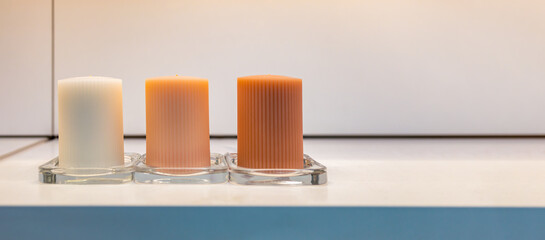 close up of white, orange and dark orange candles on white shelf