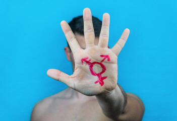 close-up of the hand of an unrecognizable young man with the trans logo drawn on a blue background