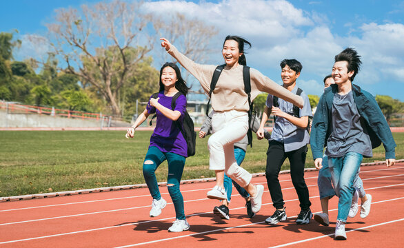 Happy young group students running Across Field