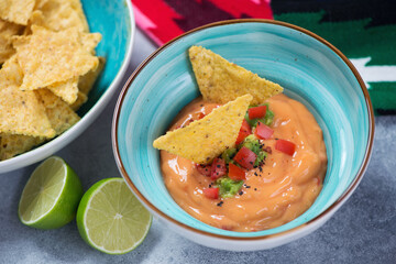 Turquoise bowl with queso or mexican cheese dip and corn chips, selective focus, horizontal shot