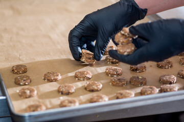 Baker forms round biscuits from the raw rolled dough on a baking sheet. Preparation for baking