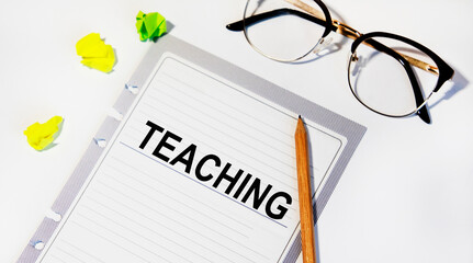 On a sheet from the diary of the tets Teaching, next to a pencil and glasses.