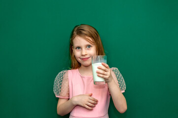 Baby girl holding a glass of milk in her hands